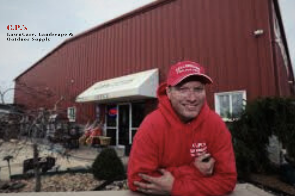 A smiling man in a red sweatshirt and cap stands in front of a large red building with a white awning. Text on the image reads C.P.s LawnCare, Landscape & Outdoor Supply. Shrubs and outdoor items are nearby.