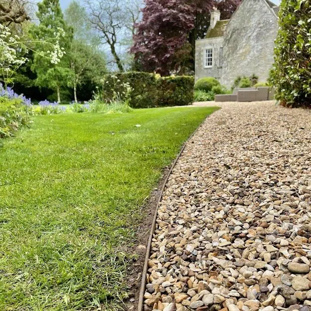 Pea gravel landscape stones pathway with metal edging showing proper installation technique